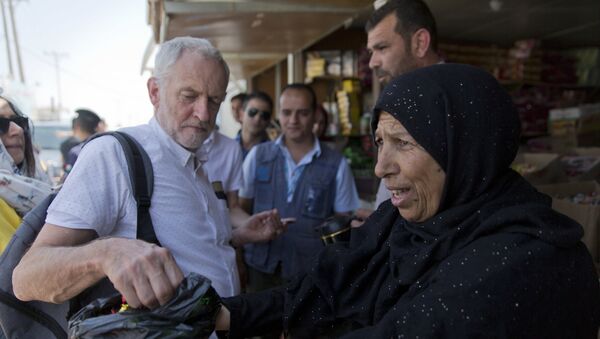 The UK's Labour party leader Jeremy Corbyn is offered candy by Syrian refugee Sohela Sobeihi, 52 while talking to refugees at the main market road, during his visit to the Zaatari Syrian Refugee Camp, in Mafraq, Jordan, June 22, 2018 - Sputnik International