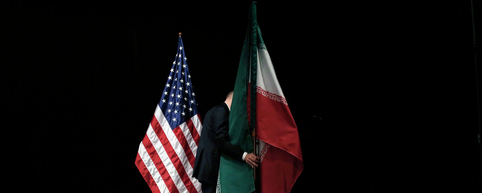 A staff member removes the Iranian flag from the stage after a group picture with foreign ministers and representatives of Unites States, Iran etc. - Sputnik International, 1920, 28.02.2021