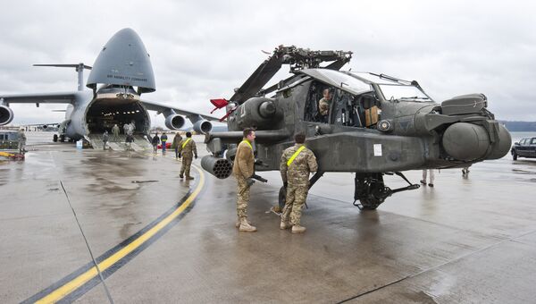 An AH-64 Apache attack helicopter stands in front of a Galaxy C-5 transport plane at the US Air Base in Ramstein, western Germany, February 22, 2017. - Sputnik International