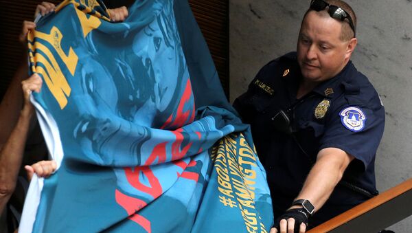 A U.S. Capitol Police officer attempts to take a protest banner from demonstrators calling for an end to family detention and in opposition to the immigration policies of the Trump administration, at the Hart Senate Office Building on Capitol Hill in Washington, U.S. June 28, 2018 - Sputnik International