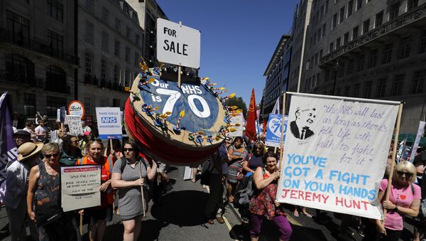 People holding placards attend a demonstration and celebration march to mark the 70th anniversary of the National Health Service (NHS), in central London on June 30, 2018 - Sputnik International