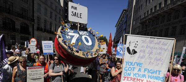 People holding placards attend a demonstration and celebration march to mark the 70th anniversary of the National Health Service (NHS), in central London on June 30, 2018 People holding placards attend a demonstration and celebration march to mark the 70th anniversary of the National Health Service (NHS), in central London on June 30, 2018 - Sputnik International