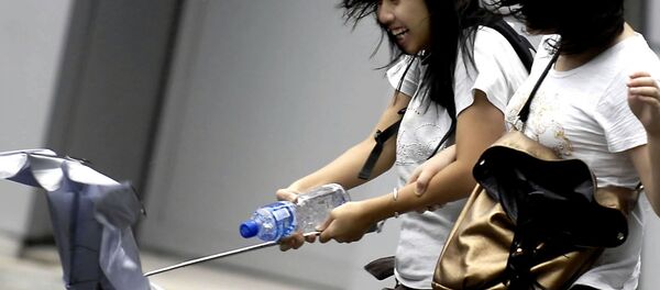 In this photo released by China's Xinhua News Agency, passers-by struggle in the street with an umbrella almost blown off in Hong Kong, south China (File) In this photo released by China's Xinhua News Agency, passers-by struggle in the street with an umbrella almost blown off in Hong Kong, south China (File) - Sputnik International