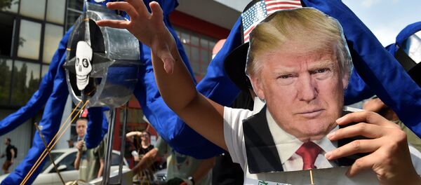 A participant holds the portrait of U.S. President Donald Trump as protesters take part in a march against the NATO leaders summit, in Brussels, Belgium July 7, 2018. - Sputnik International