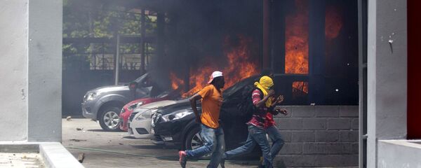 People run away after cars were set on fire at a Nissan dealership during protests over a fuel price increase in Port-au-Prince, Haiti, on Saturday, July 7, 2018 People run away after cars were set on fire at a Nissan dealership during protests over a fuel price increase in Port-au-Prince, Haiti, on Saturday, July 7, 2018 - Sputnik International