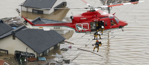 An aerial view shows a local resident being rescued from a submerged house by rescue workers using helicopter at a flooded area in Kurashiki, southern Japan, in this photo taken by Kyodo July 7, 2018 - Sputnik International