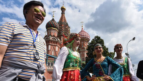 A tourist poses for a picture next to women wearing traditional dresses at Moscow's Red Square on July 10, 2015 - Sputnik International