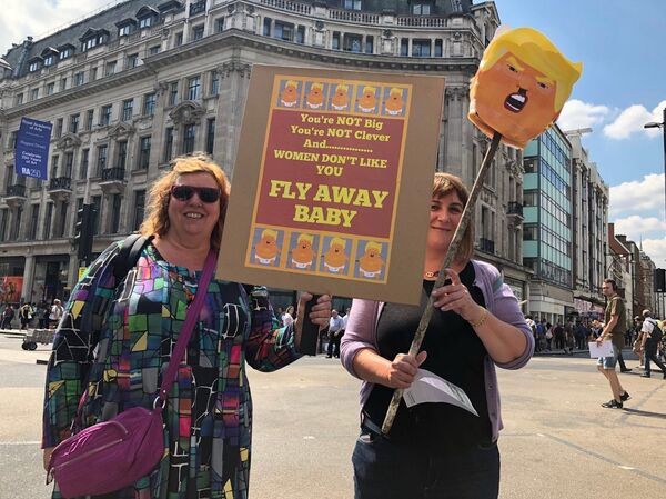 Demonstrators holding a sign telling Trump to fly away baby - Sputnik International