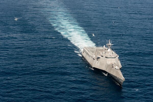 A SeaHawk, to the left, and a Fire Scout, just above the ship, perform simultaneous flight operations.  - Sputnik International