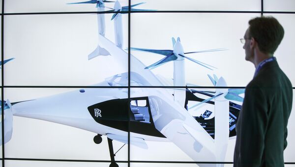 A man poses alongside screens presenting the Rolls-Royce EVTOL air taxi concept during the Farnborough Airshow, south west of London, on July 16, 2018 - Sputnik International