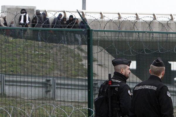 Migrants, background, watch French gendarmes patrolling on the road leading to the port in Calais, northern France, Friday Feb.2, 2018. Police reinforcements are arriving in the French port city of Calais after clashes among migrants left 22 people injured, as the interior minister warned of a worrying spike in violence - Sputnik International