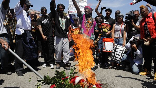 People chant slogans as they burn a U.S. flag outside the Los Angeles office of U.S. Rep. Maxine Waters, Thursday, July 19, 2018, in Los Angeles. - Sputnik International