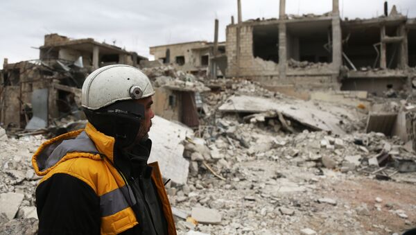 Forty-five-year-old Samir Salim (L) who along with his three brothers are members of the White Helmets rescue forces looks out at destroyed buildings in the town of Medeira in Syria's rebel-held Eastern Ghouta area on February 12 2018. - Sputnik International