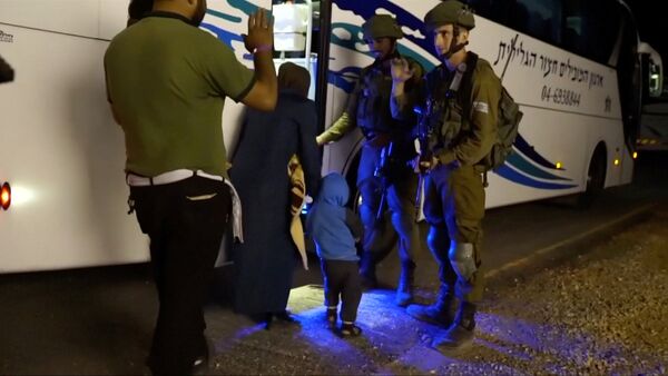 People walk past Israeli soldiers as they board a bus during the Syria Civil Defence, also known as the White Helmets, extraction from the Golan Heights, Israel in this still image taken from video, provided by the Israeli Army July 22, 2018 - Sputnik International