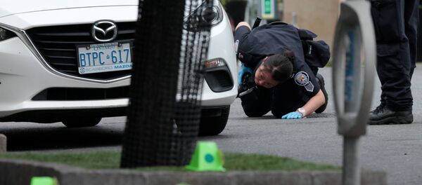 A police officer looks for evidence under a car while investigating a mass shooting on Danforth Avenue in Toronto, Canada, July 23, 2018. A police officer looks for evidence under a car while investigating a mass shooting on Danforth Avenue in Toronto, Canada, July 23, 2018. - Sputnik International