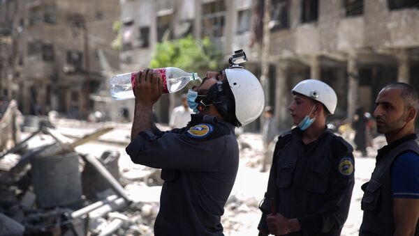 (File) Syrian civil defence volunteers, known as the White Helmets, take a break as they work at the site of a reported air strike in the rebel-held town of Douma, on the eastern outskirts of the capital Damascus, on October 5, 2016 - Sputnik International