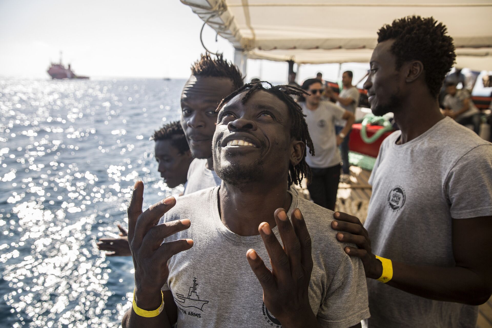 Migrants aboard the Open Arms aid boat, of Proactiva Open Arms Spanish NGO, react as the ship approaches the port of Barcelona, Spain, Wednesday, July 4, 2018. The aid boat sailed to Spain with 60 migrants rescued on Saturday in waters near Libya, after it was rejected by both Italy and Malta - Sputnik International, 1920, 20.12.2021