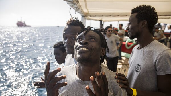 Migrants aboard the Open Arms aid boat, of Proactiva Open Arms Spanish NGO, react as the ship approaches the port of Barcelona, Spain, Wednesday, July 4, 2018. The aid boat sailed to Spain with 60 migrants rescued on Saturday in waters near Libya, after it was rejected by both Italy and Malta - Sputnik International