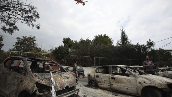 A firefighting helicopter flies above burned-out cars in Mati east of Athens, Tuesday, July 24, 2018. Twin wildfires raging through popular seaside areas near the Greek capital have torched homes, cars and forests and killed at least 49 people, authorities said Tuesday, raising the death toll after rescue crews reported finding the bodies of more than 20 people huddled together near a beach - Sputnik International
