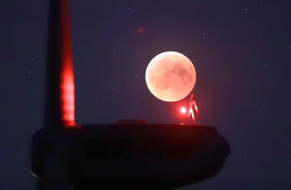 The blades from a wind turbine are silhouetted against the moon in the sky in Novogrudok, Belarus, during a total lunar eclipse on Saturday, July 28, 2018. Skywatchers around much of the world are looking forward to a complete lunar eclipse that will be the longest this century. The blades from a wind turbine are silhouetted against the moon in the sky in Novogrudok, Belarus, during a total lunar eclipse on Saturday, July 28, 2018. Skywatchers around much of the world are looking forward to a complete lunar eclipse that will be the longest this century. - Sputnik International