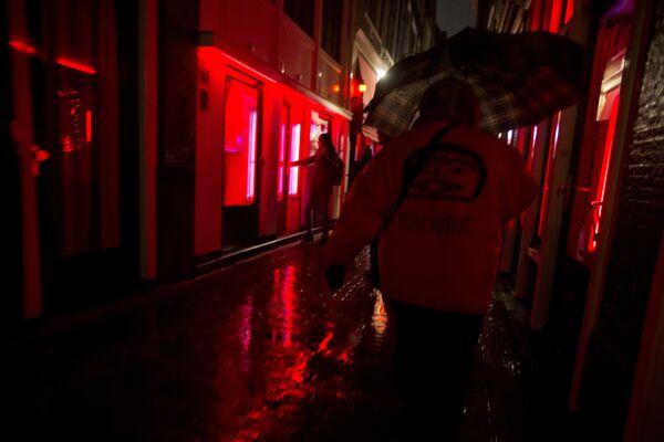 People walk through a narrow alley in the Red Light district in Amsterdam, Netherlands, Friday, Dec. 8, 2017. Every weekend, the heart of the historic port city, with its strip joints, seedy bars and scantily-clad prostitutes flaunting themselves behind plate glass windows, is overrun by foreign visitors over for stag and hen nights or to smoke marijuana in one of the city's many coffee shops. People walk through a narrow alley in the Red Light district in Amsterdam, Netherlands, Friday, Dec. 8, 2017. Every weekend, the heart of the historic port city, with its strip joints, seedy bars and scantily-clad prostitutes flaunting themselves behind plate glass windows, is overrun by foreign visitors over for stag and hen nights or to smoke marijuana in one of the city's many coffee shops. - Sputnik International
