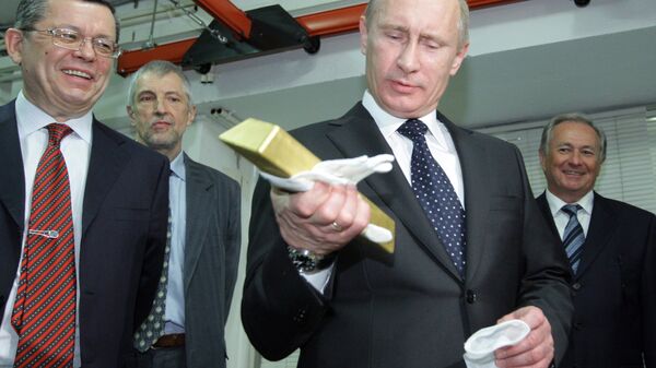 Vladimir Putin holding a gold bar while visiting the Central Depository of the Bank of Russia. - Sputnik International