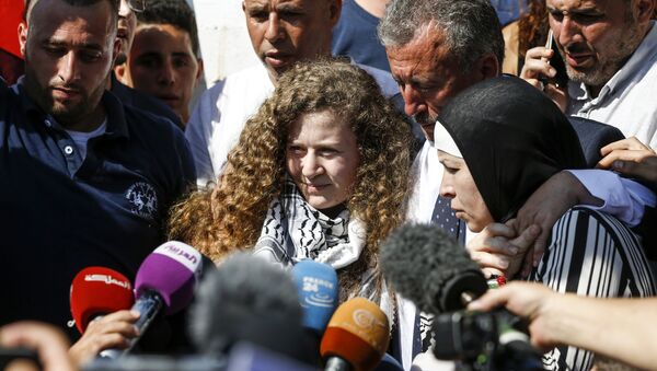 Palestinian activist and campaigner Ahed Tamimi (C) speaks to reporters upon her release from prison after an eight-month sentence for slapping two Israeli soldiers, on the outskirts of the West Bank village of Nabi Saleh on July 29, 2018, as she is accompanied by her father (C-R) and mother (R) - Sputnik International