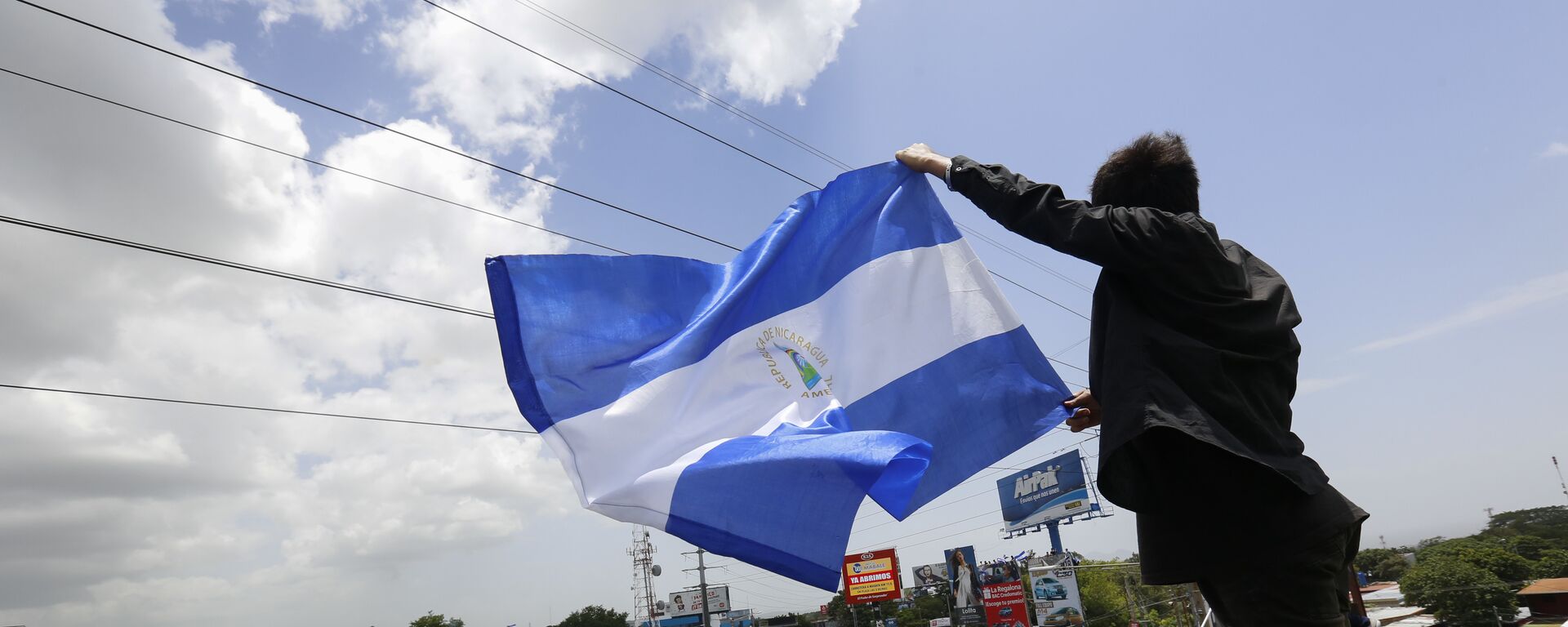 A man waves a Nicaraguan flag as people participate in a demonstration - Sputnik International, 1920, 05.08.2020