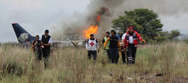 In this photo released by Red Cross Durango communications office, Red Cross workers and rescue workers carry an injured person on a stretcher, right, as airline workers, left, walk away from the site where an Aeromexico airliner crashed in a field near the airport in Durango, Mexico, Tuesday, July 31, 2018 In this photo released by Red Cross Durango communications office, Red Cross workers and rescue workers carry an injured person on a stretcher, right, as airline workers, left, walk away from the site where an Aeromexico airliner crashed in a field near the airport in Durango, Mexico, Tuesday, July 31, 2018 - Sputnik International
