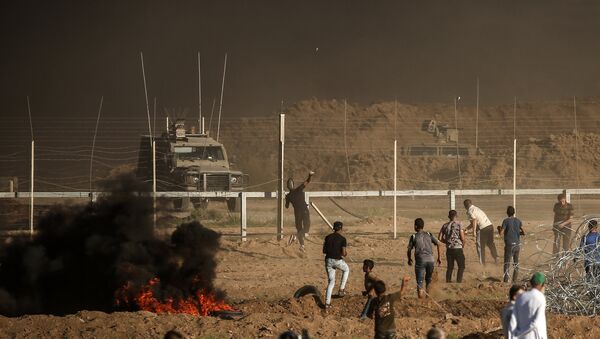 Palestinian protesters throw stones towards Israeli forces during a demonstration along the border between Israel and the Gaza strip, east of Gaza city on July 27, 2018 - Sputnik International