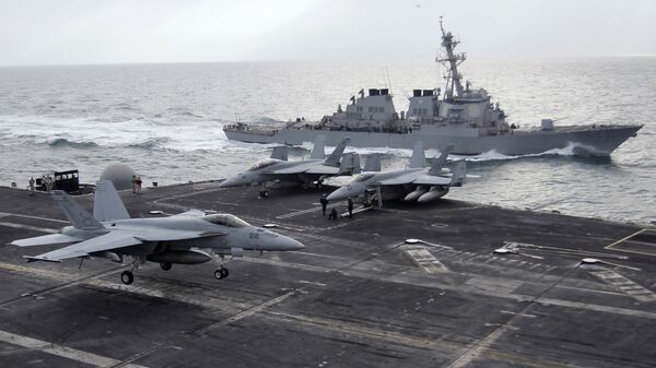 This file photo taken on Monday, Feb. 13, 2012 shows a U.S. F-18 fighter jet, left, land on the Nimitz-class aircraft carrier USS Abraham Lincoln (CVN 72) as a U.S. destroyer sells on alongside during fly exercises in the Persian Gulf - Sputnik International