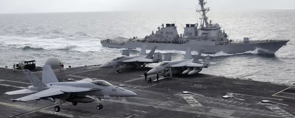 This file photo taken on Monday, Feb. 13, 2012 shows a U.S. F-18 fighter jet, left, land on the Nimitz-class aircraft carrier USS Abraham Lincoln (CVN 72) as a U.S. destroyer sells on alongside during fly exercises in the Persian Gulf - Sputnik International