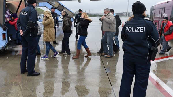 Police officers escort rejected refugees who are boarding an aircraft at the airfield of the Franz-Josef-Strauss airport in Munich, southern Germany, on December 9, 2015, as the plane brings rejected asylum seekers back to their country - Sputnik International