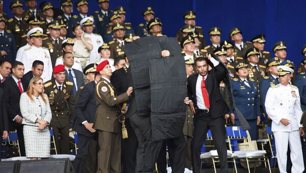 In this photo released by China's Xinhua News Agency, security personnel surround Venezuela's President Nicolas Maduro during an incident as he was giving a speech in Caracas, Venezuela, Saturday, Aug. 4, 2018 - Sputnik International
