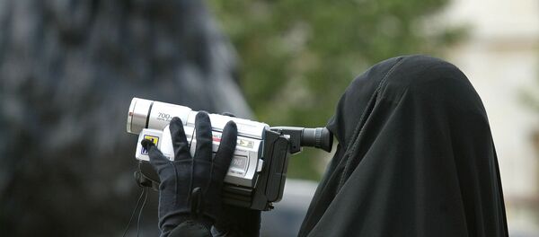 A woman in traditional Muslim gowns videofilms her family under the watchful eyes of the lions guarding the Nelson column at Trafalgar square in London, 12 August 2002. - Sputnik International