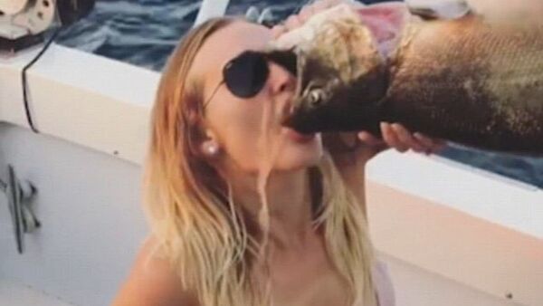 The woman is seen chugging beer out of a dead fish's mouth - Sputnik International