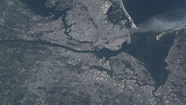 Visible from space, a smoke plume rises from the Manhattan area after two planes crashed into the towers of the World Trade Center. This photo was taken of metropolitan New York City (and other parts of New York as well as New Jersey) the morning of September 11, 2001. - Sputnik International