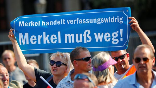 People hold a banner reading: Merkel is acting unconstitutionally, Merkel must leave as they take part in a protest against German Chancellor Angela Merkel as she visits the state parliament in Dresden, Germany August 16, 2018. - Sputnik International