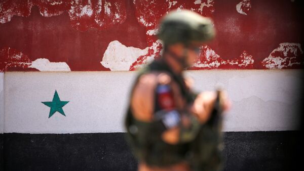 A Russian soldier stands guard near a Syrian national flag - Sputnik International