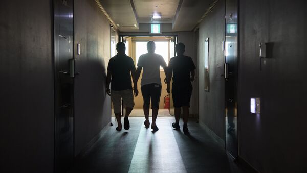 A group of asylum seekers walk along a hallway (File) - Sputnik International