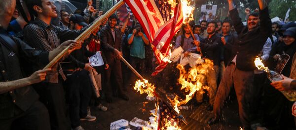 Iranians burn US flags during an anti-US demonstration outside the former US embassy headquarters in the capital Tehran on May 9, 2018. - Sputnik International