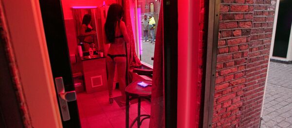 A prostitute waits for clients behind her window in the red light district of Amsterdam on December 8, 2008. A prostitute waits for clients behind her window in the red light district of Amsterdam on December 8, 2008. - Sputnik International