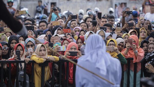 People use their mobile phones to take pictures as a Shariah law official whips a woman who is convicted of prostitution during a public caning outside a mosque in Banda Aceh, Indonesia, Friday, April 20, 2018. Indonesia's deeply conservative Aceh province on Friday caned several unmarried couples for showing affection in public and two women for prostitution before an enthusiastic audience of hundreds. The canings were possibly the last to be carried out before large crowds in Aceh after the province's governor announced earlier this month that the punishments would be moved indoors - Sputnik International