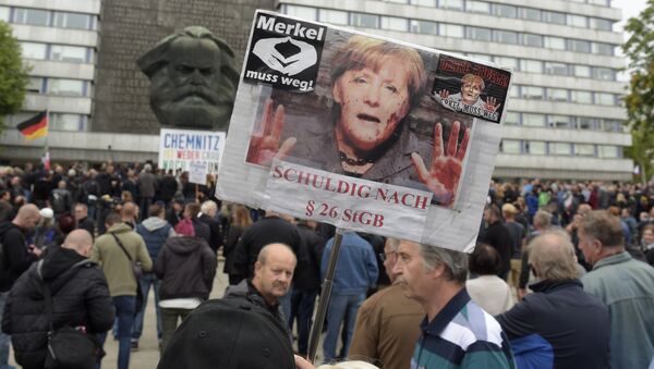 A protestor holds a poster with a photo of Angela Merkel reading 'Merkel must go and referring she is guilty of incitement in Chemnitz, eastern Germany, Saturday, Sept. 1, 2018, after several nationalist groups called for marches protesting the killing of a German man last week, allegedly by migrants from Syria and Iraq - Sputnik International