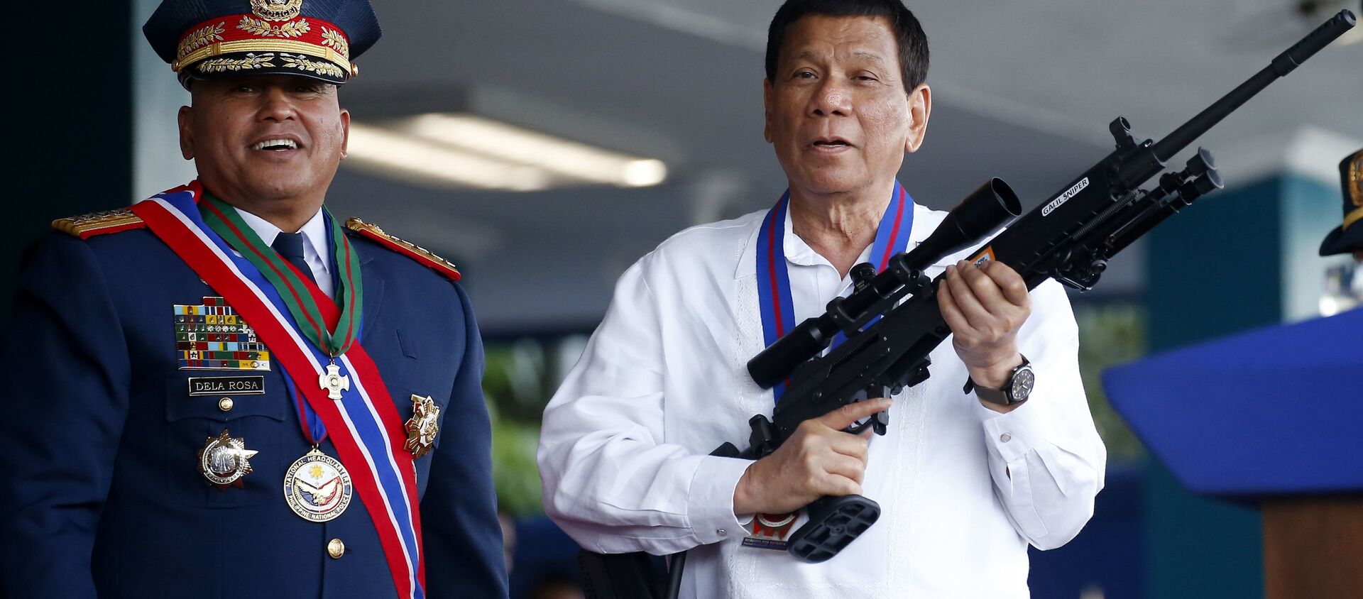 April 19, 2018 file photo, Philippine President Rodrigo Duterte, right, jokes to photographers as he holds an Israeli-made Galil rifle which was presented to him by former Philippine National Police Chief Director General Ronald Bato Dela Rosa at the turnover-of-command ceremony at the Camp Crame in Quezon city northeast of Manila - Sputnik International, 1920, 22.06.2021