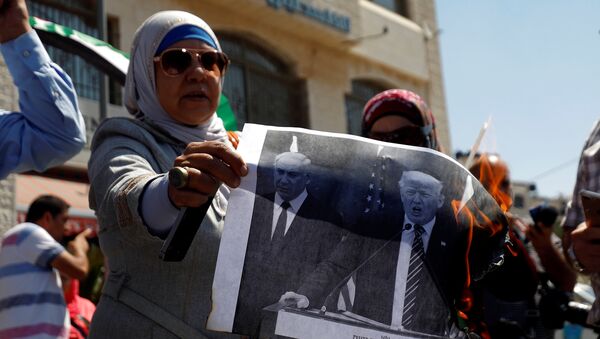A Palestinian woman burns a picture of U.S. President Donald Trump and Israeli Prime Minister Benjamin Netanyahu during a protest against a U.S. decision to cut funding to the United Nations Relief and Works Agency (UNRWA), in Ramallah, in the occupied West Bank September 4, 2018. - Sputnik International