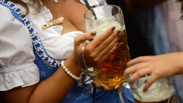 A young woman wearing the Bavarian traditional dress Dirndl holding a beer - Sputnik International