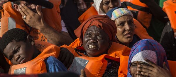 Migrants aboard a rubber dinghy off the Libyan coast receive aid from rescuers aboard the Open Arms aid boat, of Proactiva Open Arms Spanish NGO, Saturday, June 30, 2018. - Sputnik International