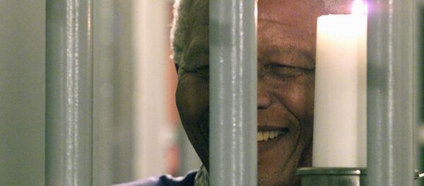 Former South African President Nelson Mandela holds a symbolic millennium candle 31 December 1999 in his cell at the prison of Robben Island where he was imprisoned for 27 years during the apartheid time. - Sputnik International