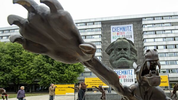 People walk between sculptures by artist Rainer Opolka in front of the Karl Marx Monument in Chemnitz, eastern Germany, Thursday, Sept. 13, 2018. The figure in the foreground is one of 10 life-sized metal wolf sculptures as a part of the spontan exhibition 'Wolves with Hitler salute howl in front of the Karl-Marx-Monument', to protest against xenophobia and right-wing extremism. - Sputnik International